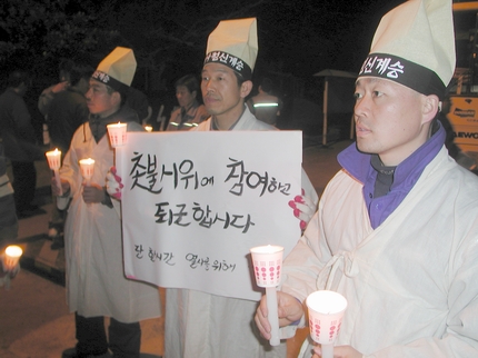 두산중공업 해고자들이 17일 퇴근자들에게 촛불시위에 동참해 줄 것을 호소하며 서 있는 모습. 